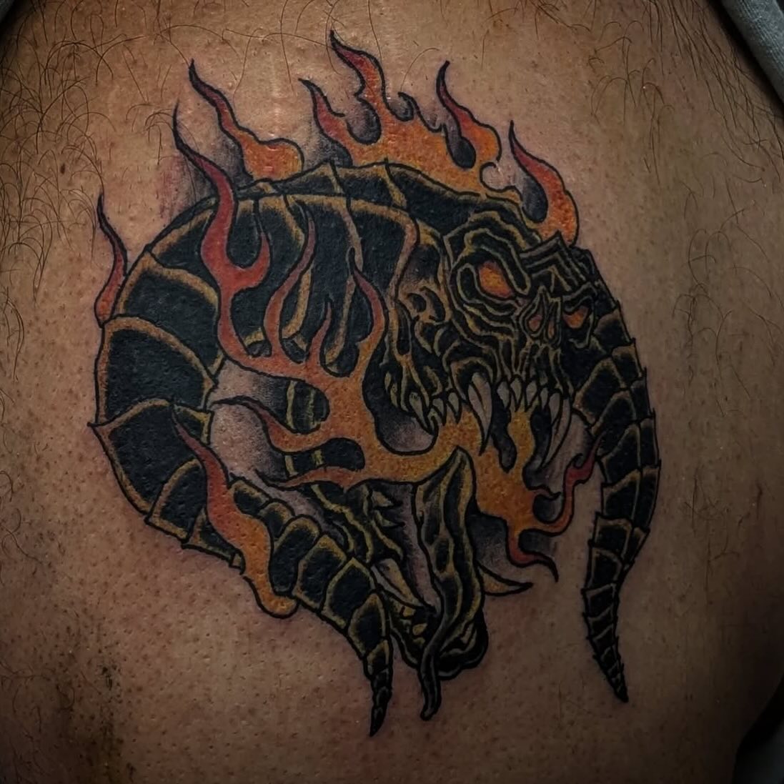Dark creature tattoo wrapped in orange flames